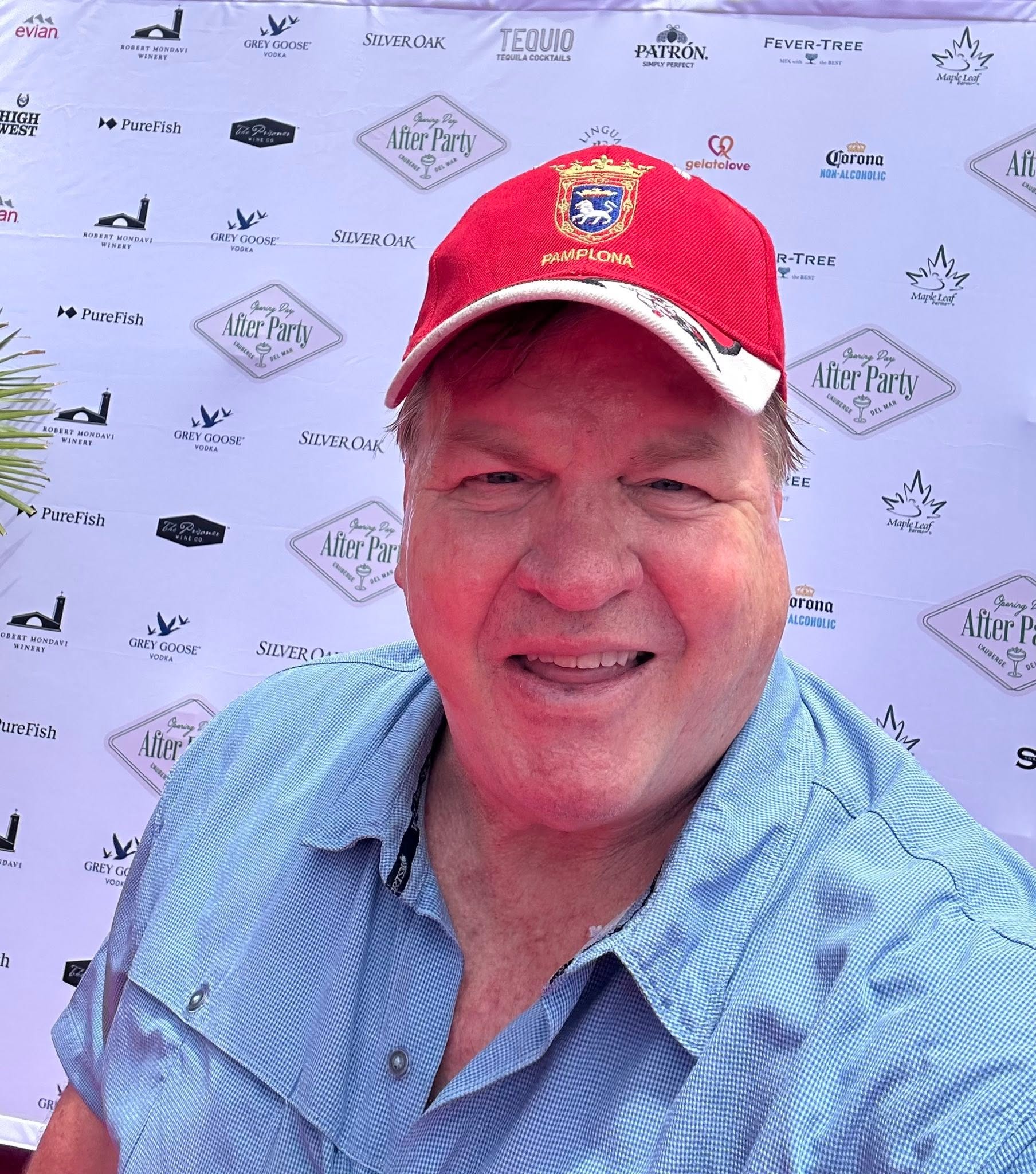 Kirk Webster smiling in a red Pamplona cap at a Del Mar event