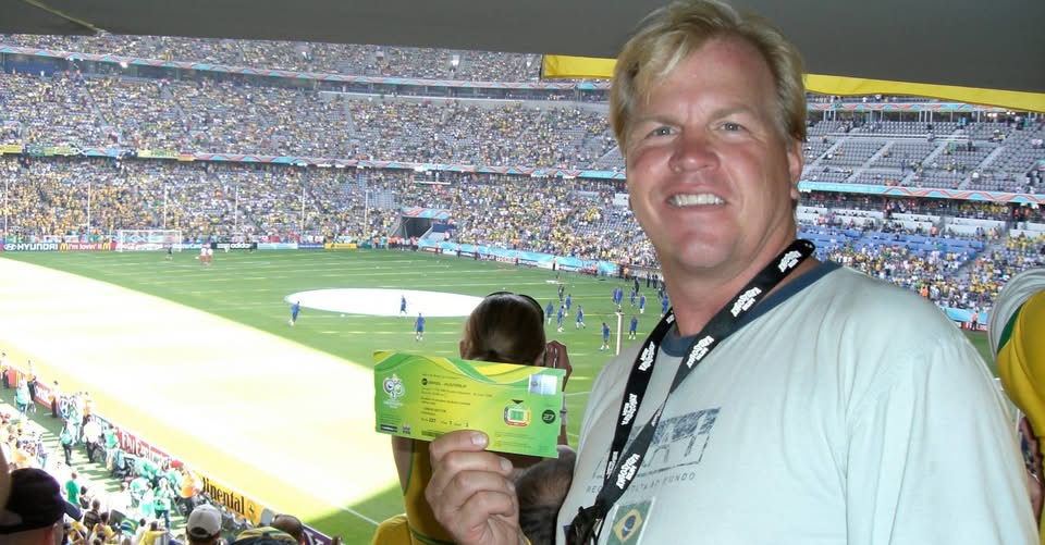 Kirk Webster holding a FIFA World Cup ticket inside a packed stadium